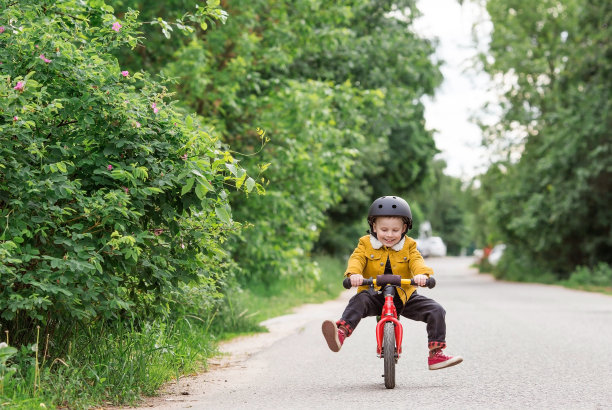 一个快乐的小男孩戴着头盔在户外骑着跑步自行车。一个快乐的孩子正在从事一项积极的运动。保护。人寿保险和儿童安全。图片下载