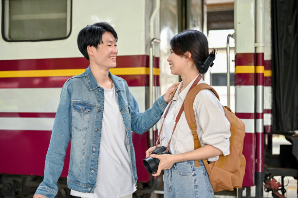 一对可爱的年轻亚洲游客夫妇在上车前在站台上聊天图片下载