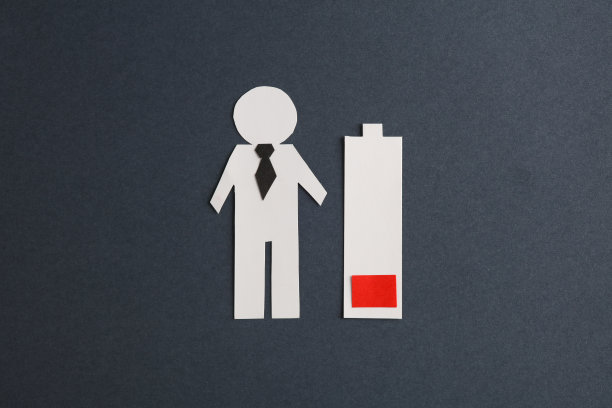 剪纸商人和低电池在深灰色背景。经营理念图片下载