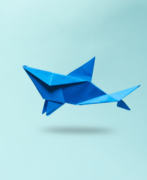 折纸鲨鱼漂浮在一个蓝色的背景图片下载