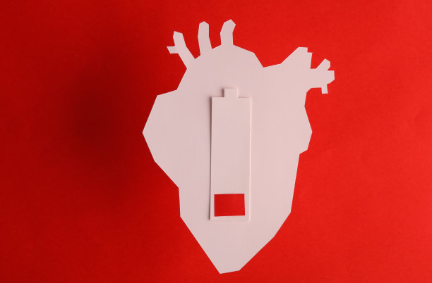 剪纸解剖心脏和低电池在一个红色的背景。心脏疾病图片下载