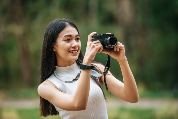 手持数码相机在自然公园休息的年轻女子肖像图片下载