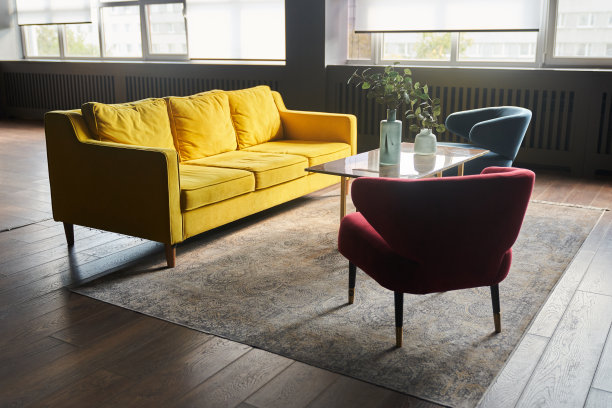 部分室内配有黄色沙发和2把扶手椅，蓝色和红色，杂志桌和地毯。背景上的窗户，桌子上的装饰，花瓶和复制空间。高质量照片图片下载