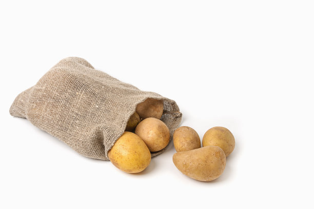 新鲜的白土豆从袋子里洒出来，洒在白色的背景上。孤立的图片下载