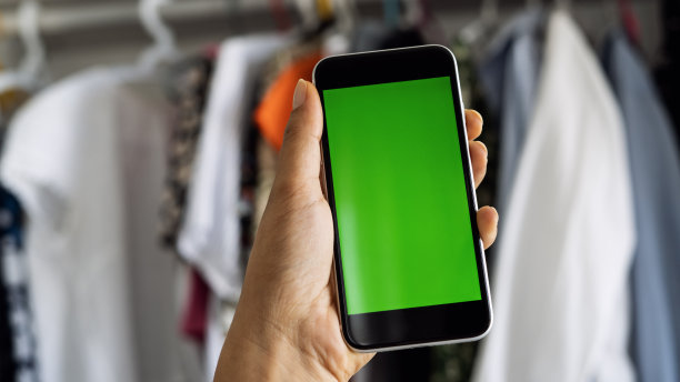 手拿绿屏智能手机，前面有很多衣服图片下载