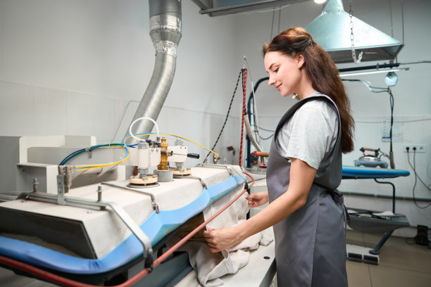 洗衣房的操作员小心地将衣服放入蒸汽印刷机图片下载