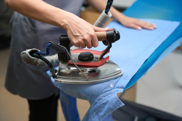 一名妇女正在用电器熨衬衣，去除皱纹图片下载