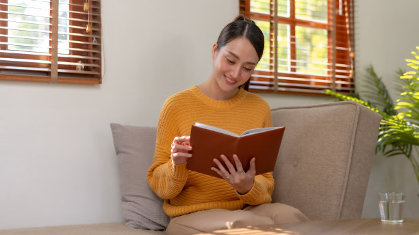 有魅力和美丽的亚洲女性在家里读书和工作，他们的闲暇和享受阅读的假期。图片下载