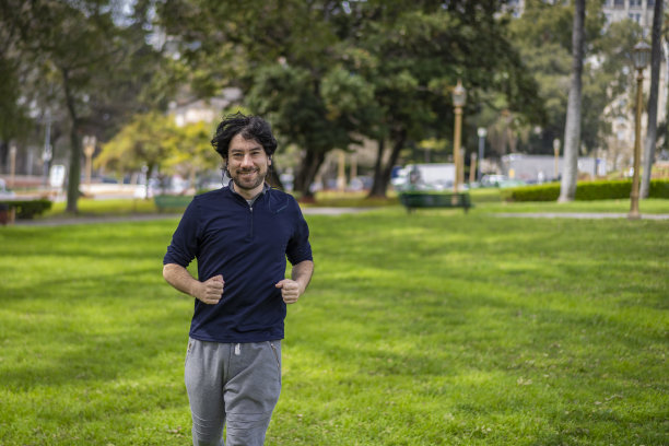 英俊迷人成熟大胡子拉丁男子40多岁穿着休闲蓝色t恤在公园跑步的肖像图片下载
