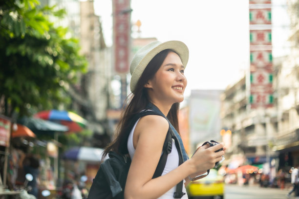 年轻的成年亚洲吃货女背包旅行者在唐人街街头小吃吃亚洲甜点。旅行女孩们正在享受曼谷美丽的地方，图片下载