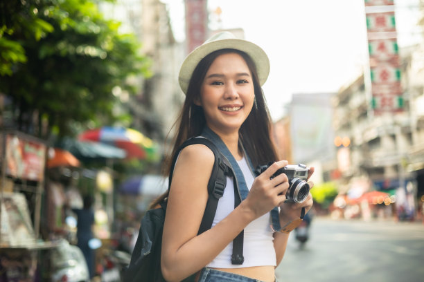 年轻的成年亚洲吃货女背包旅行者在唐人街街头小吃吃亚洲甜点。旅行女孩们正在享受曼谷美丽的地方，图片下载