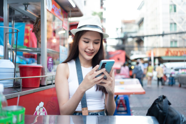 年轻的成年亚洲吃货女背包旅行者在唐人街街头小吃吃亚洲甜点。旅行女孩们正在享受曼谷美丽的地方，图片下载