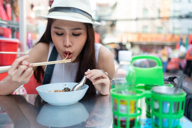 年轻的成年亚洲吃货女背包旅行者在唐人街街头小吃吃亚洲甜点。旅游女孩们正在享受曼谷美丽的地方。图片下载