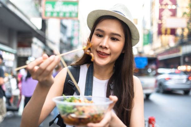 年轻的成年亚洲吃货女背包旅行者在唐人街街头小吃吃亚洲甜点。旅游女孩们正在享受曼谷美丽的地方。图片下载