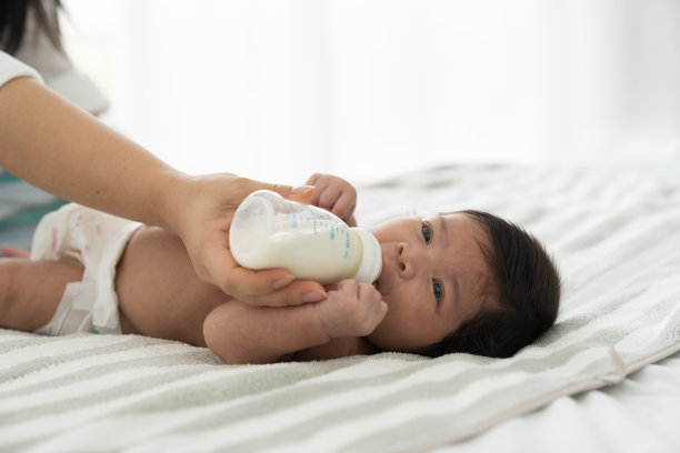 亚洲新生婴儿用母亲的乳头吃奶。母亲用奶瓶喂婴儿图片下载