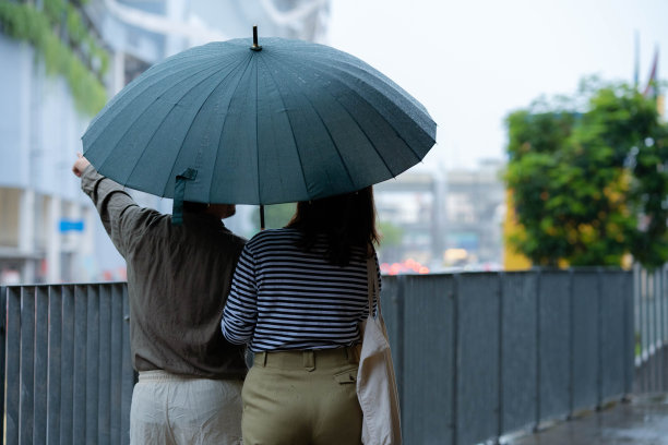 一对亚洲夫妇在下雨天打着伞一起散步图片下载