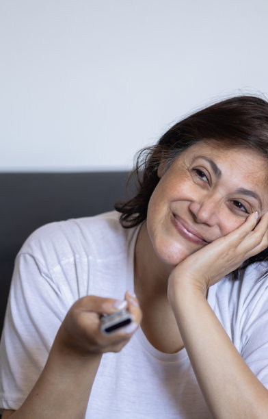 在家看电视并用遥控器换台的年长的中东妇女竖版照片图片下载