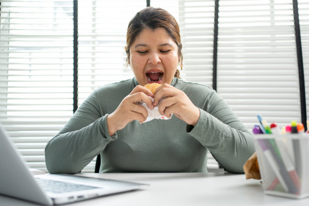 亚洲女人在办公室吃汉堡。图片下载
