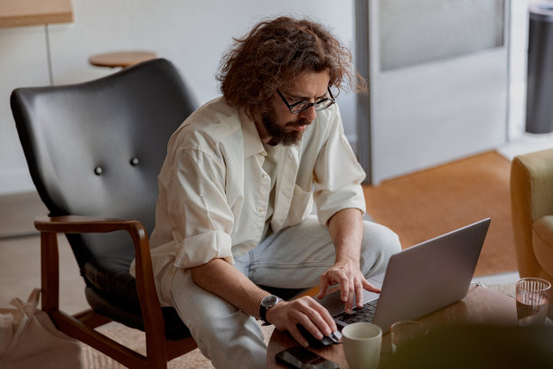 专注的男性自由职业者坐在现代联合办公的笔记本电脑上工作。远程工作概念图片下载