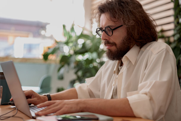 年轻的商人坐在现代联合办公的电脑上工作。远程工作概念图片下载