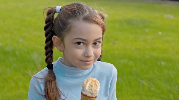 小女孩拿着冰淇淋，饶有兴趣地看着镜头图片下载
