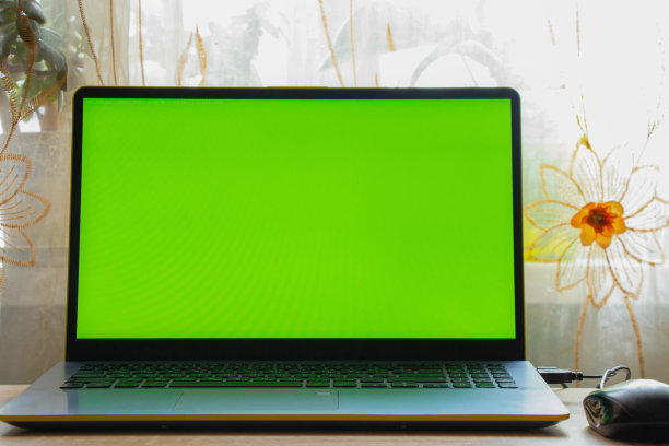 房间靠窗的桌子上放着一台绿屏笔记本电脑图片下载