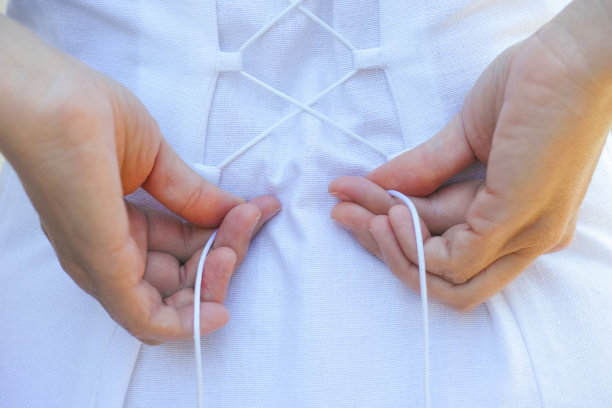 女人正在系紧衣服后面的鞋带。图片下载