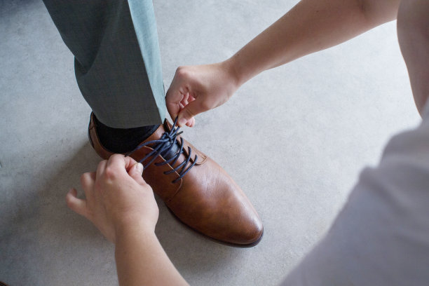 一个女人给男人系鞋带的特写图片下载