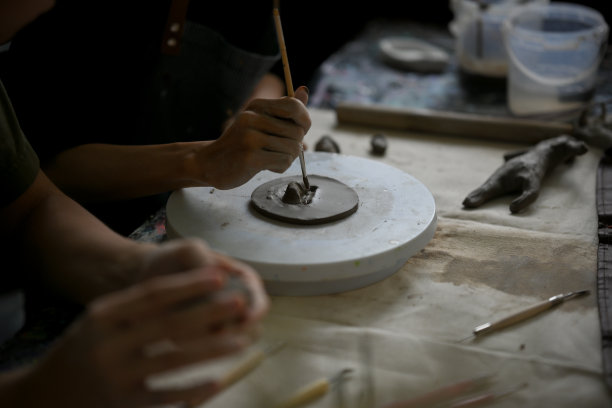 一位富有创造力的男性陶艺艺术家手持一根棍子，在未加工的粘土上制作图案图片下载