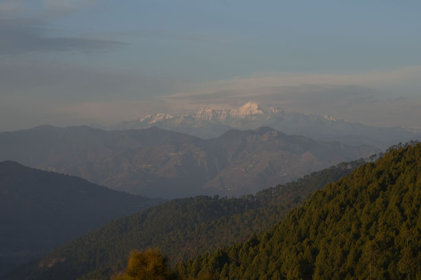 风景优美的山区景观，郁郁葱葱的绿叶和朦胧的天空为背景图片下载