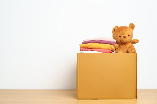 儿童捐赠，慈善，志愿者，给予和交付的理念。亲手捐赠小熊娃娃和衣服到家里的纸板箱，以支持和帮助穷人，难民和无家可归的人。文本复制空间图片下载