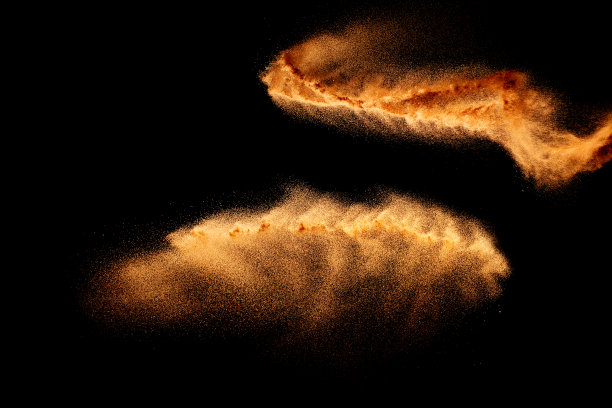干河沙爆炸。棕色的沙子溅在黑色的背景。黄沙飞舞在空中。图片下载