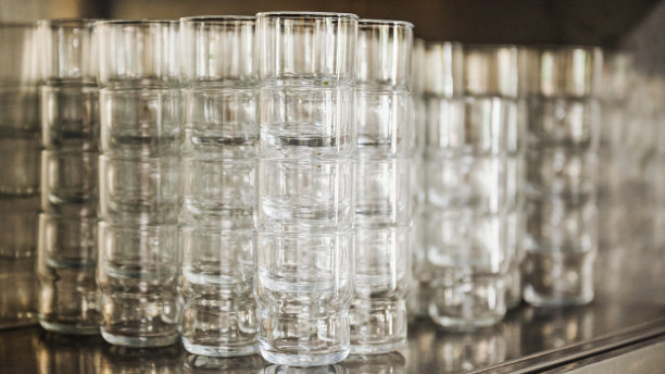 很多相同的，堆叠的，普通的，普通的玻璃杯。强烈模糊，锐度在后玻璃上图片下载