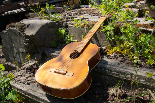 一把古老的棕色木制吉他躺在乌克兰春草地上的一条石头路上图片下载