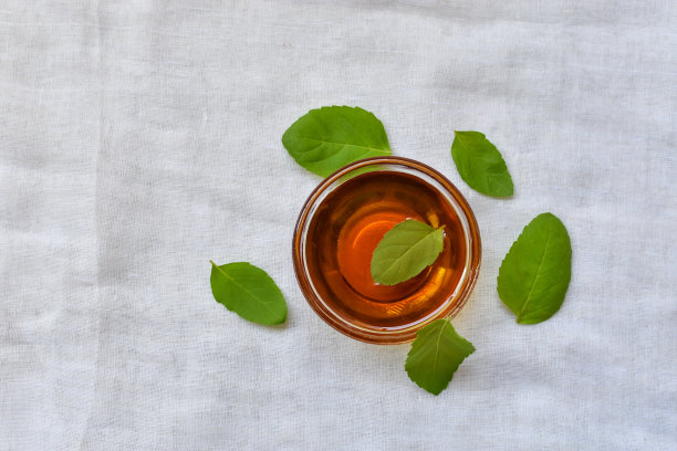 圣罗勒或土尔西的新鲜叶子与生蜂蜜的特写，这是治疗哮喘发作和咳嗽的家庭疗法。绿茶成分，土丝和蜂蜜图片下载