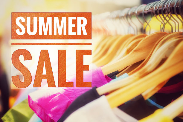 夏季大减价的横幅挂在色彩模糊的衣服上，栏杆上挂着木制衣架图片下载