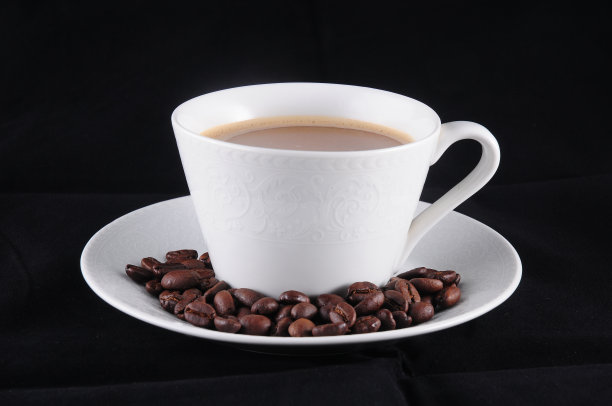 桌上有一杯咖啡和咖啡豆。黑色背景图片下载