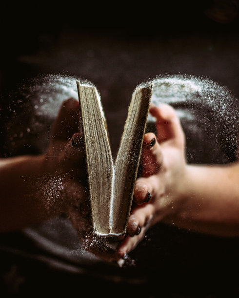 一个人打开一本发霉的精装书，导致一阵灰尘颗粒被释放到空气中图片下载