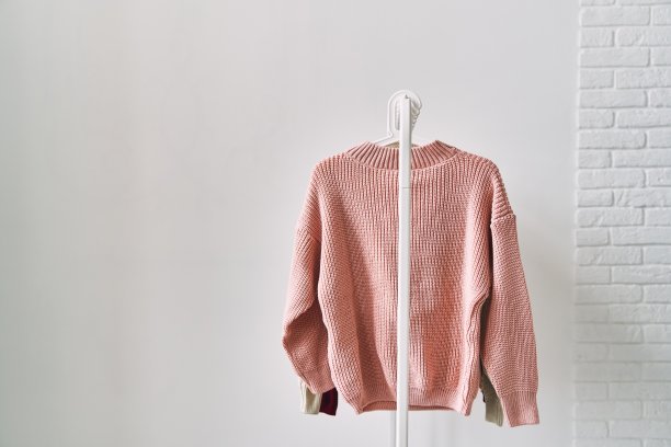 一件白色背景的羊毛衫挂在衣架上。保暖衣物大甩卖。图片下载