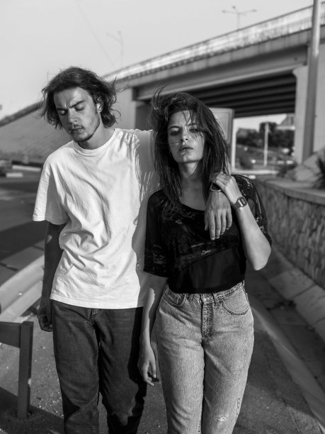 一对穿着垃圾牛仔布的时尚情侣走在桥下的城市街道上图片下载