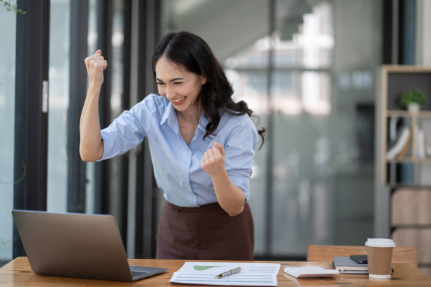 兴奋快乐的女孩赢家看着笔记本庆祝成功。图片下载