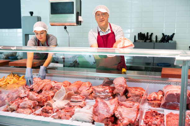 上了年纪的肉店小贩在展示柜里摆着生排骨图片下载