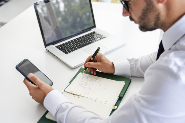 一个商人的后视图，发短信和使用笔记本电脑工作图片下载