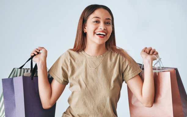 快乐的女人，购物袋和肖像隔离在工作室背景财富，财务自由或促销。零售，时尚和年轻的混血儿或z世代客户手持纸袋图片下载