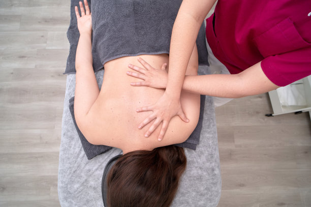 匿名理疗师的手放在病人背上的特写图片下载