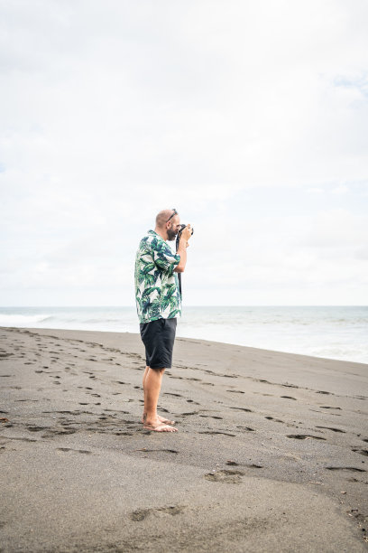 一名男子在海滩上用数码相机拍照图片下载