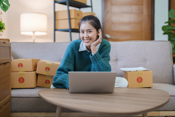 独立的亚洲女性创业企业家微笑着使用电脑笔记本电脑与愉快的成功的网络营销包装物品和中小企业配送概念图片下载