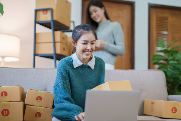 独立的年轻亚洲女性在线卖家正在使用电脑和接受订单包装产品以交付给客户。中小企业交付理念图片下载