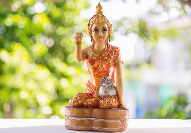 一个美丽的老女人雕像坐在招手快乐的命运与绿色的自然背景。图片下载