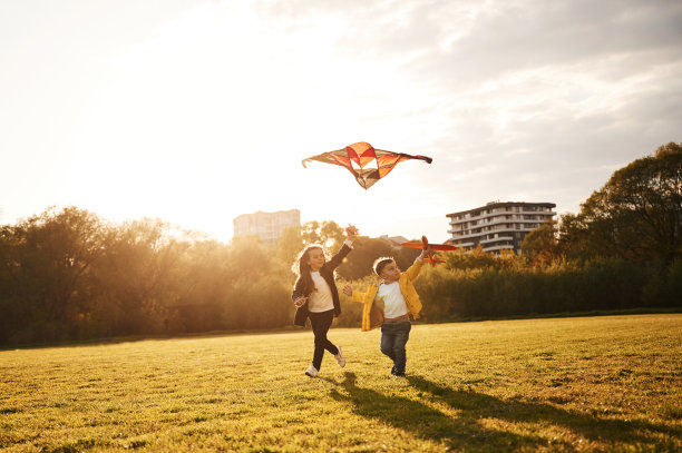 两个孩子在夏天的操场上玩风筝图片下载